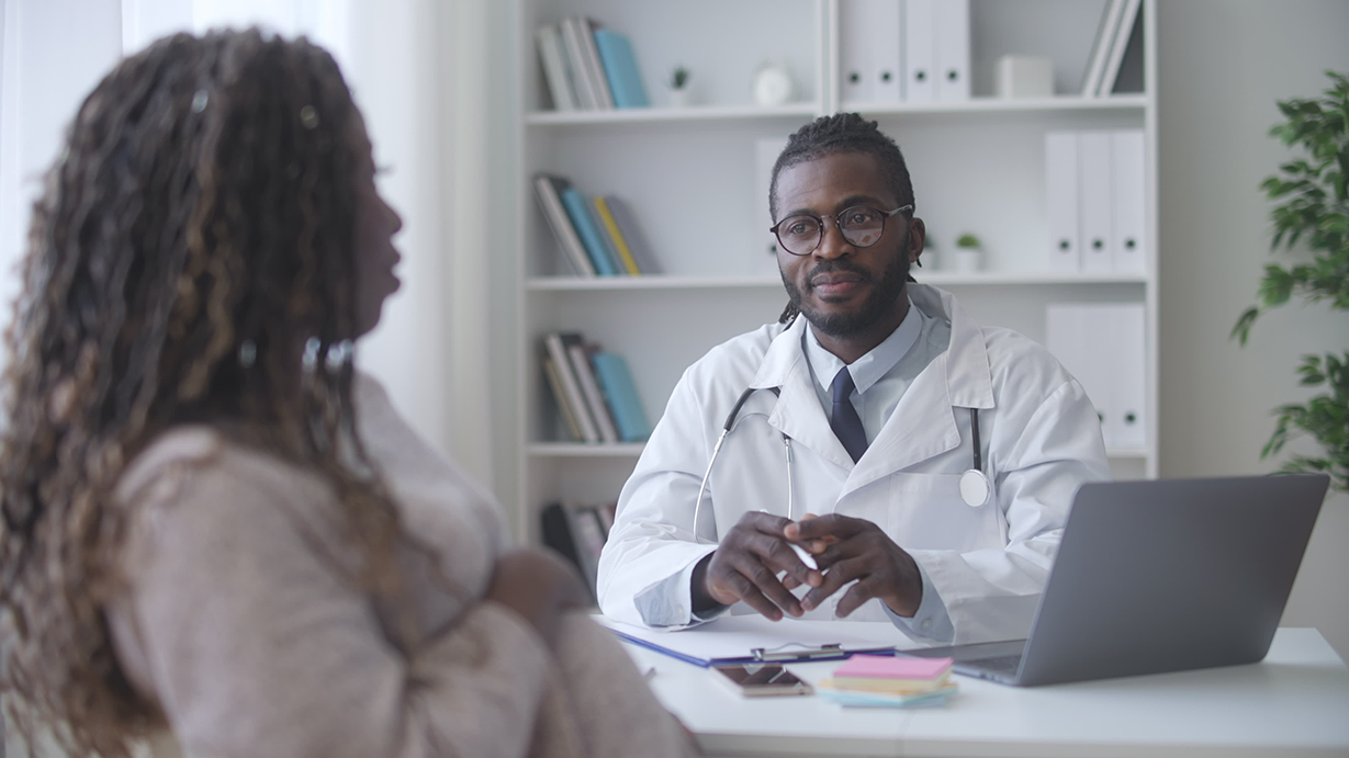 Black doctor speaking with pregnant black mom.